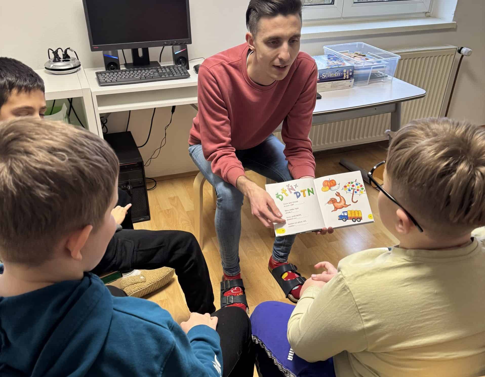 Česká skupina dětí s lektorem při čtení knihy, školní aktivity, vzdělávání, rozvoj dětí.