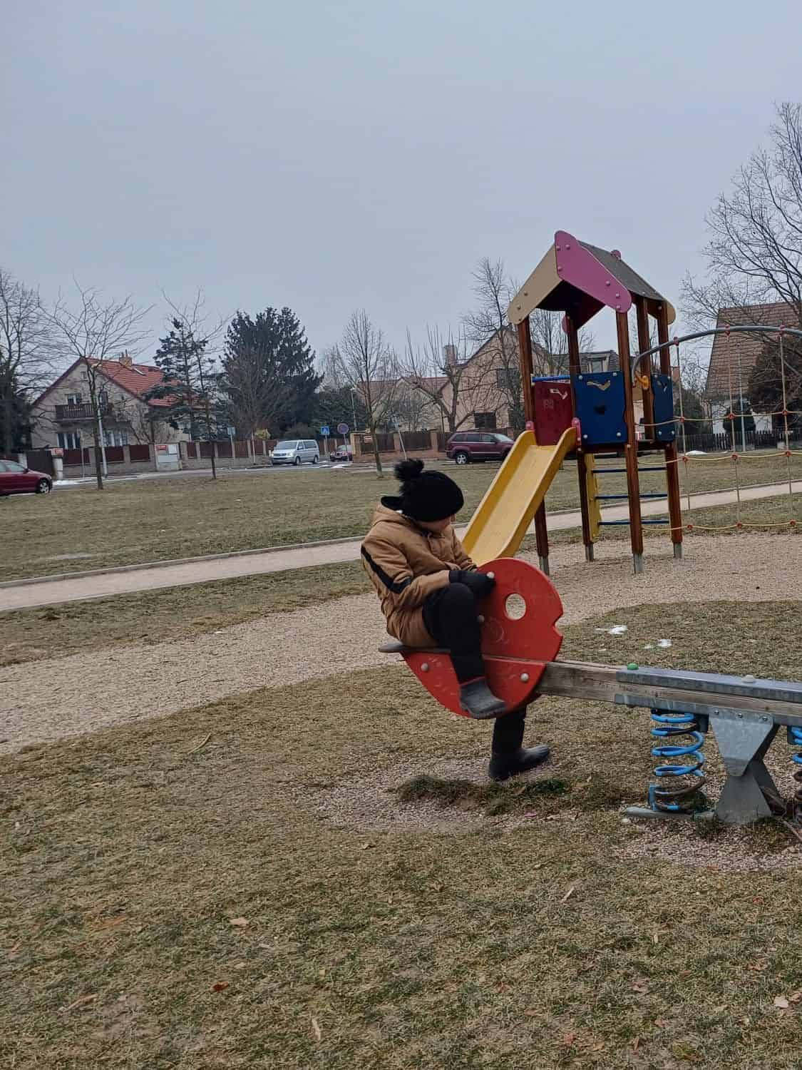 Hra na houpačce v místním dětském hřišti, ideální pro rozvoj dovedností dětí a zábavu na čerstvém vzduchu.